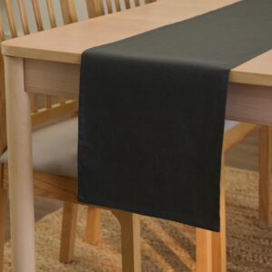 Kolgrå bordslöpare i canvas draperad över ett träbord.