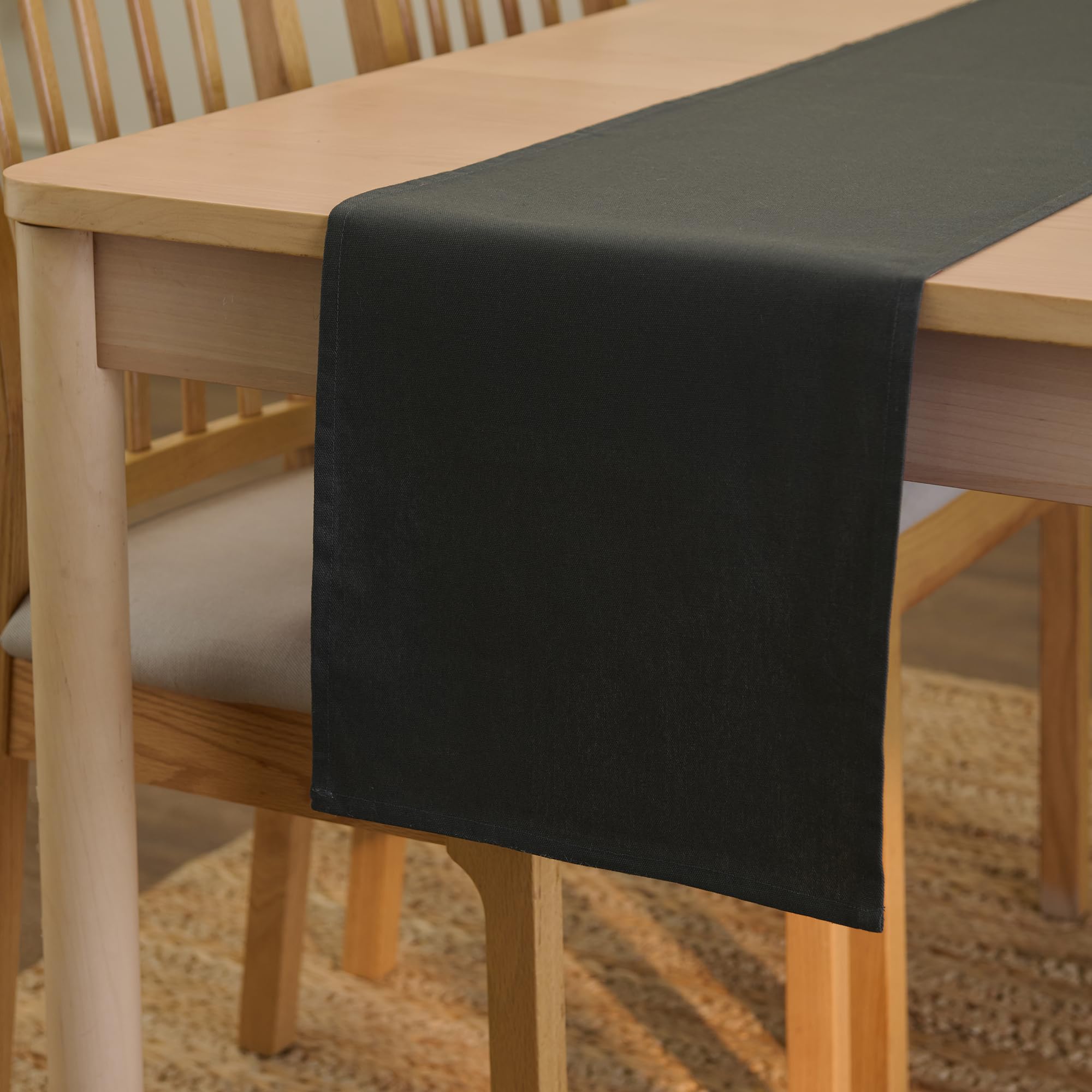 Kolgrå bordslöpare i canvas draperad över ett träbord.