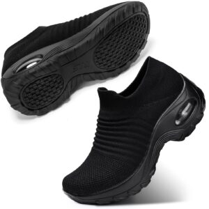 Ett par svarta slip-on-skor, med en sko liggande och en upprätt.