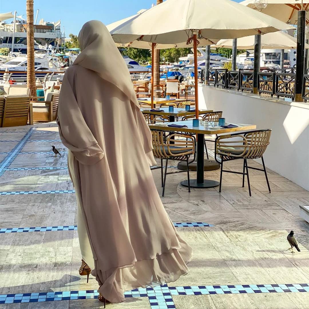 Beige öppen abaya i kaftanstil, sedd bakifrån på en uteservering.