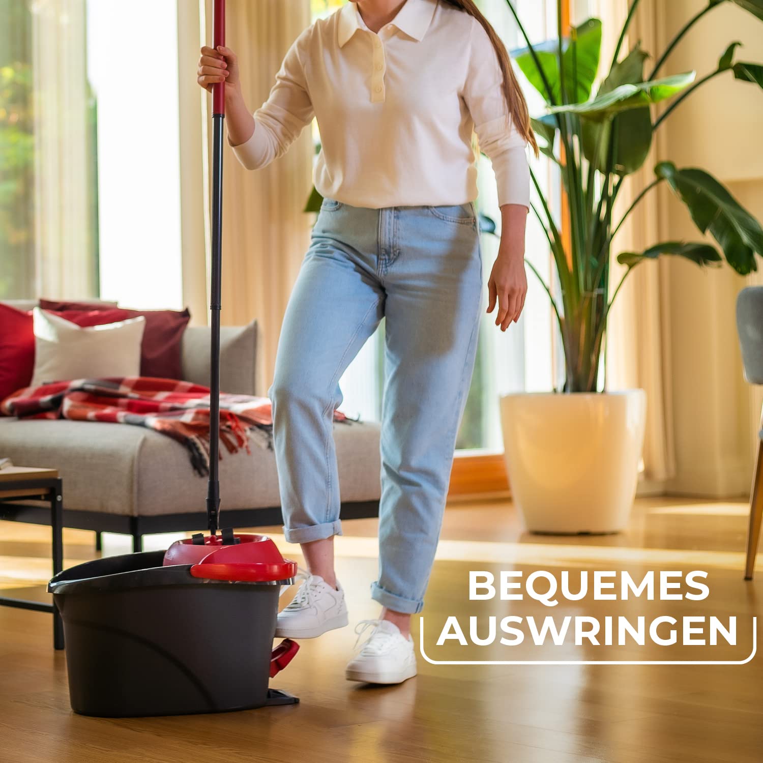 Person använder ett moppsystem med hink i ett vardagsrum.