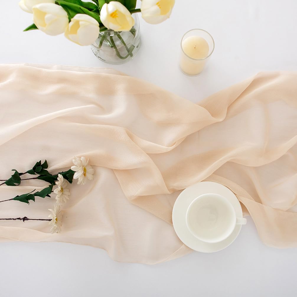 Beige bordslöpare i chiffong med tulpaner, blommor, ljus och vit kopp ovanpå.