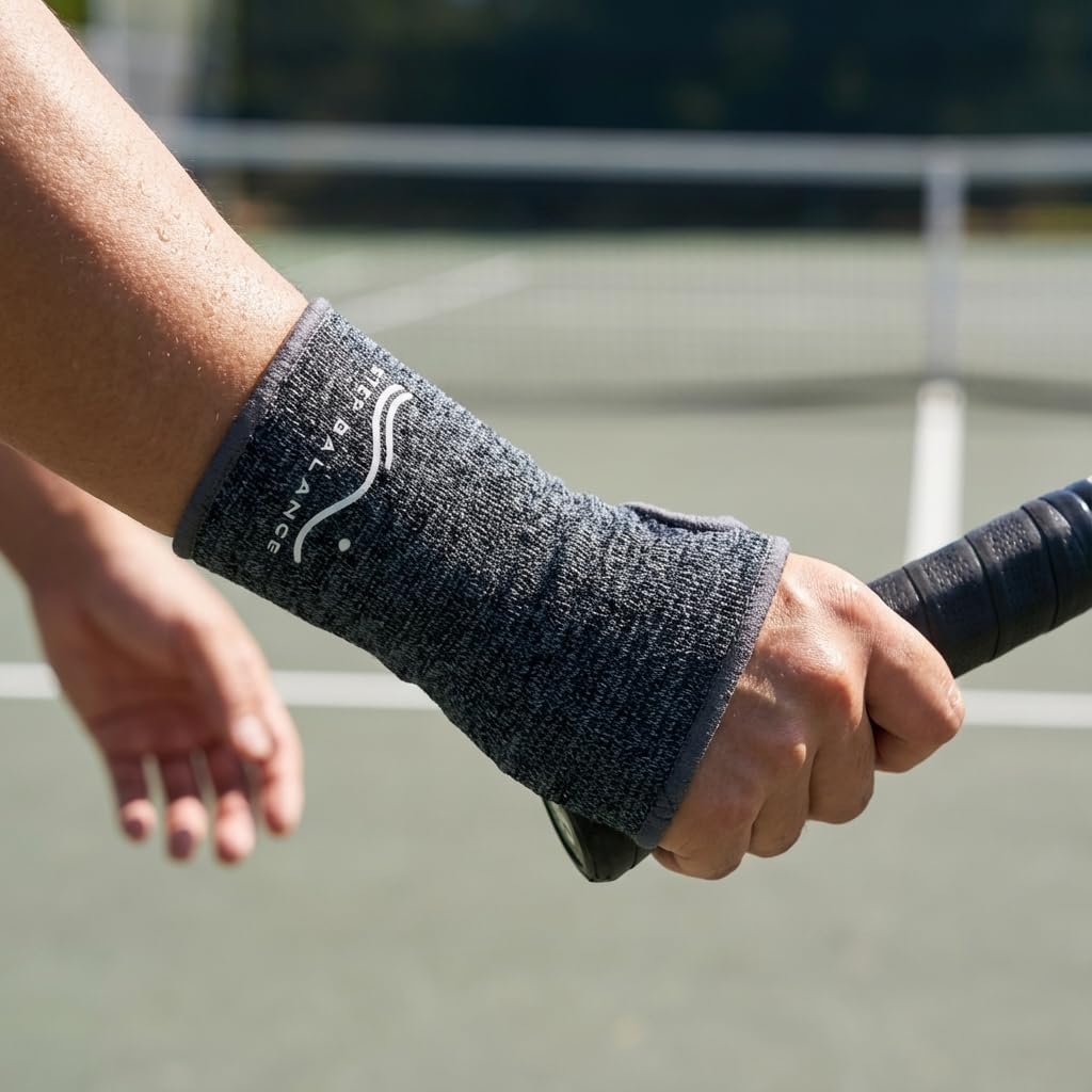 Grått handledsstöd med kompression på en hand som håller i ett tennisracket.