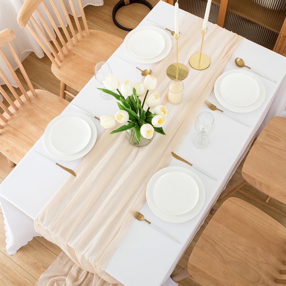 Beige bordslöpare på dukat matbord med tallrikar, bestick, ljusstakar och blommor.