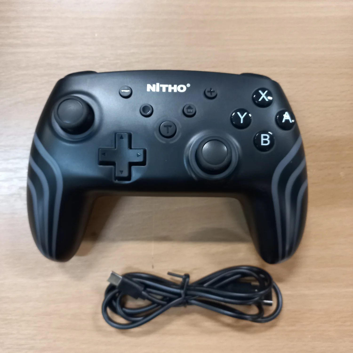 NITHO-spelkontroll med två styrspakar och medföljande kabel på träyta
