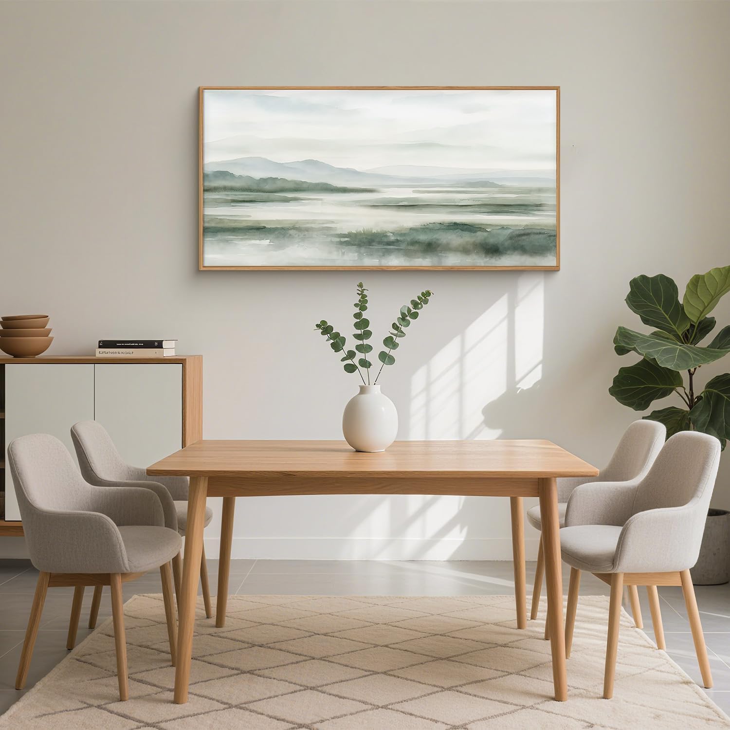 Grön abstrakt landskapstavla med träram ovanför ett matbord i ett ljust hem.
