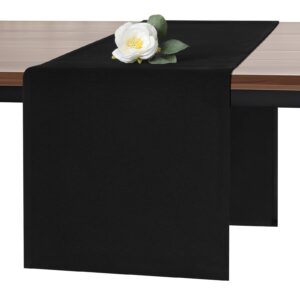Svart bordslöpare över ett träbord, dekorerad med en vit blomma.