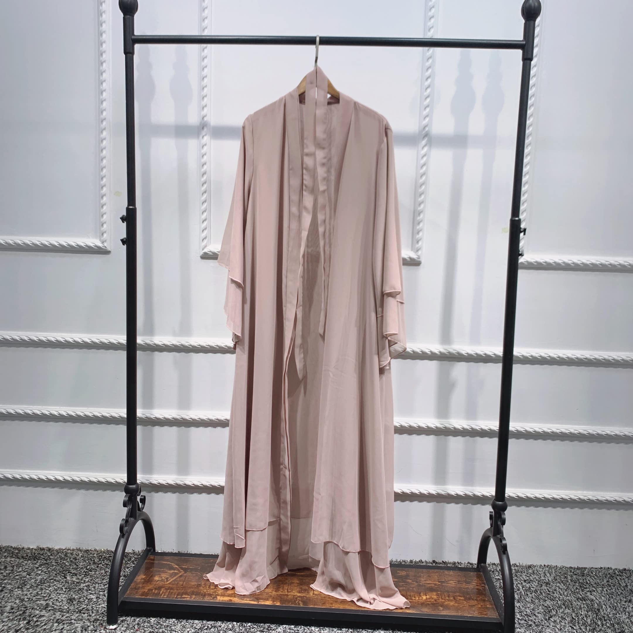 Lång beige öppen abaya i kaftanstil hänger på en klädställning.